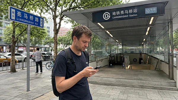 International traveler using a smartphone for navigation and ride-hailing on a city street in China